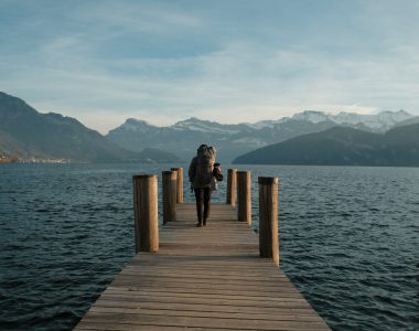 Woman walks on a pier towards mountains